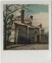 House with multiple chimneys and red and green panels on the front façade.  Gift of the Richard ...