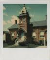 Red brick building with tower in front, multiple chimneys.  Gift of the Richard Welling Family, ...