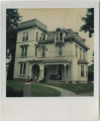 Second Empire house with group of people on the front steps and one on the porch.  Gift of the  ...