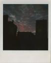 Pink and gray clouds (sunrise/sunset) over silhouette of roofs, Gift of the Richard Welling Fam…