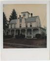 Three-story house with an overhanging porch, a gambrel roof, two chimneys and a cupola.  Gift o…