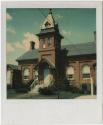 Red brick building with tower in front, multiple chimneys.  Gift of the Richard Welling Family,…