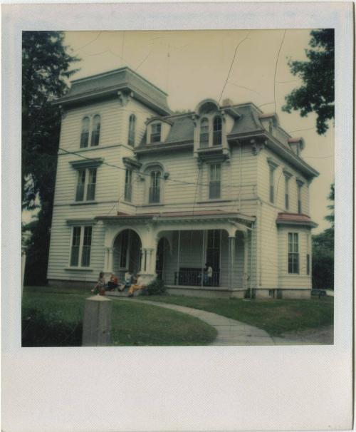 Second Empire house with group of people on the front steps and one on the porch.  Gift of the …