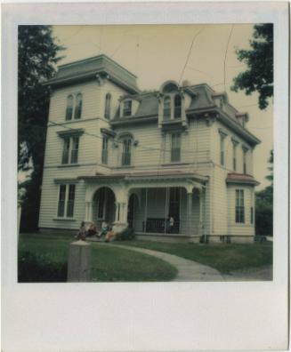 Second Empire house with group of people on the front steps and one on the porch.  Gift of the …
