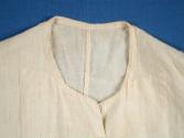 Neckline and front facing stitched to suggest collar lapel.